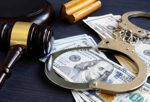 Gavel, a pair of handcuffs, and some money on a table